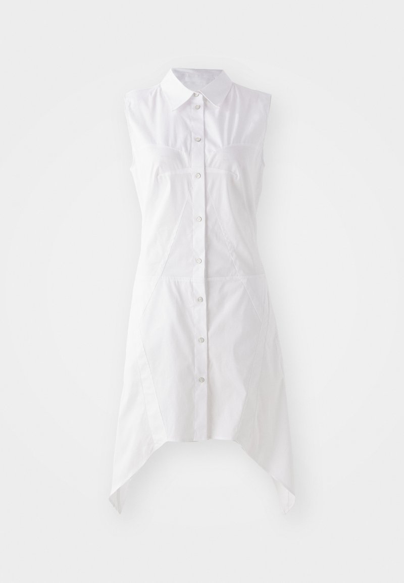 Hvid ærmeløs kjole med kraveudskæring, frontlukning med knapper, to brystlommer og en asymmetrisk kant. Lavet af vævet stof.