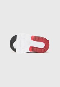 Semelle de basket au design noir, blanc et rouge. Caoutchouc texturé et design segmenté avec des motifs rectangulaires et des rainures.