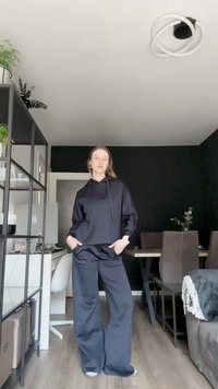 Juodas didelis džemperis su priekinėmis kišenėmis ir raišteliais, derinamas su atitinkamais plačiais kelniais. Audinys su tekstūra ir glotnia apdaila.