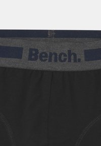 Fekete pamut alsónemű szürke rugalmas derékpánttal, amelyen sötétkék betűkkel a "Bench." felirat olvasható. Simaság jellemzi, kontrasztos varrással.