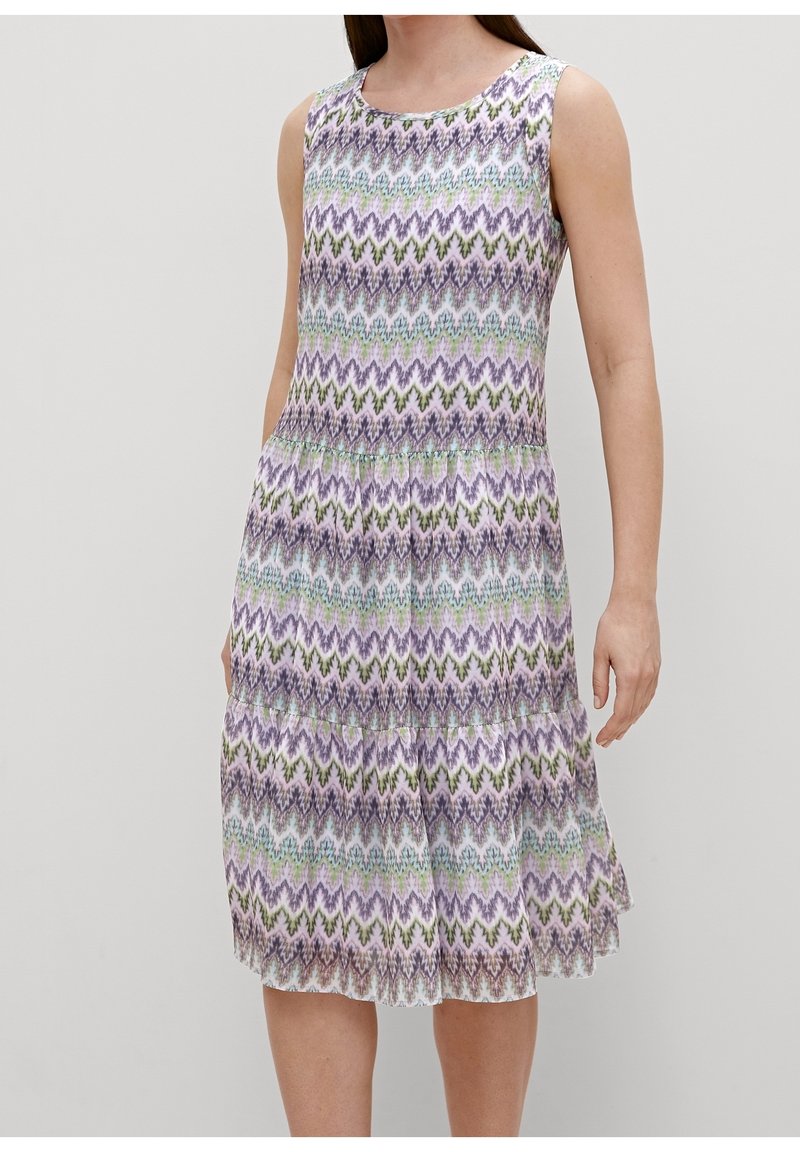 Robe sans manches longueur genou avec un motif zigzag multicolore aux tons violet, vert et bleu sur fond blanc.