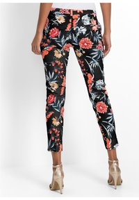 Pantalons floraux noirs avec un motif de fleurs multicolore et des accents rouges, oranges et verts ; coupe slim et longueur cheville avec poches latérales.