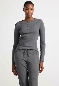 Gråt, ribstrikket hyggetøjssæt med en langærmet trøje med knaplukning og bukser med snøre i taljen og sidelommer. Blødt, tekstureret stof.