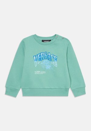 Sweatshirt verde menta com decote redondo, mangas longas e botões de pressão decorativos. Adornado com a gráfica de "VERSACE" e medusa em azul.