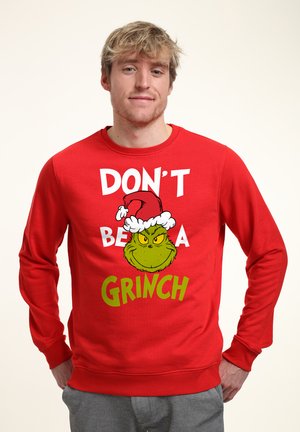 Felpa rossa con la scritta "NON ESSERE UN GRINCH" e un'illustrazione del Grinch con un cappello di Babbo Natale, dal tessuto liscio e dal collo a giro.