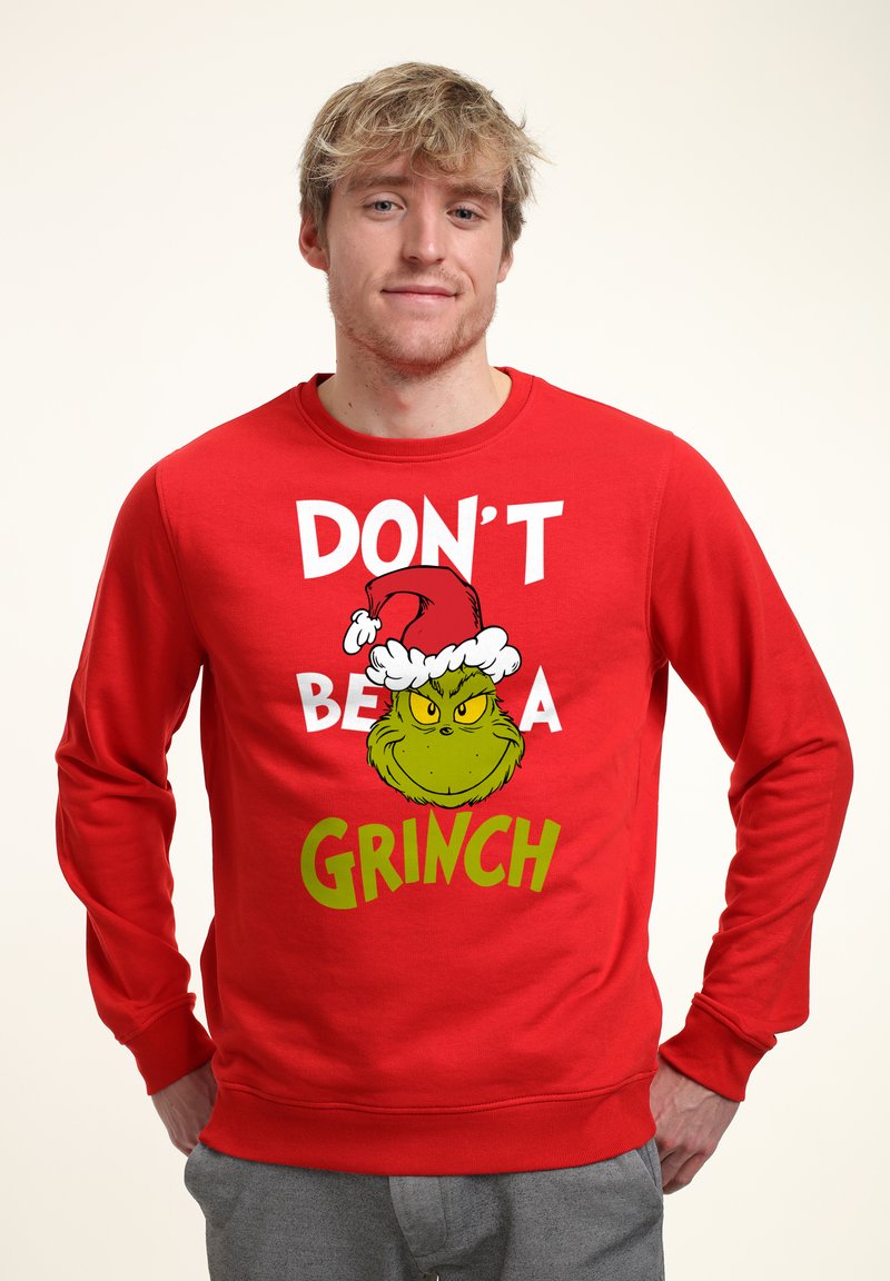 Felpa rossa con la scritta "NON ESSERE UN GRINCH" e un'illustrazione del Grinch con un cappello di Babbo Natale, dal tessuto liscio e dal collo a giro.