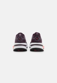 Zapatillas deportivas moradas con un upper texturizado, media suela blanca, suela negra y acentos rosas. Diseño de talón redondeado con detalle de logo.