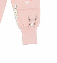 Ljusrosa barnbyxor med elastiska muddar, prydda med tryckta tecknade kaniner och hjärtan i svart och vitt på nederbenet.