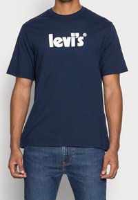 Mörkblå bomulls t-shirt med en stor vit "levi's" logotyp över bröstet, rund halsringning och korta ärmar.