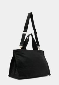 Borsa a tracolla in tela nera con doppi manici superiori e tracolla regolabile; presenta dettagli in metallo dorato e occhiali laterali distintivi.