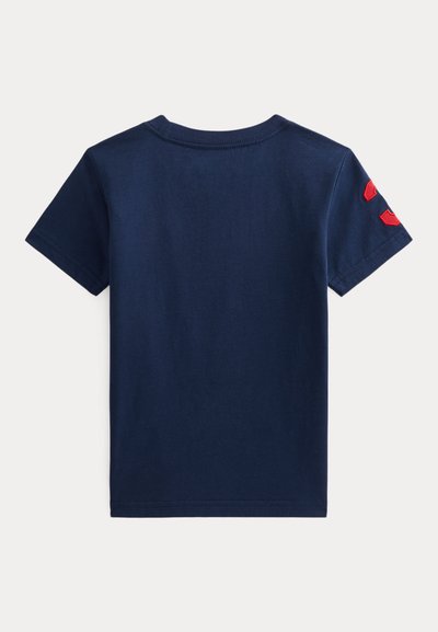 T-shirt de algodão azul-marinho com mangas curtas, apresentando três detalhes vermelhos no ombro esquerdo. Gola redonda, textura suave e corte clássico.