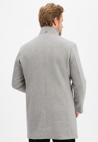 Szary wełniany płaszcz w wzór jodełki, z długimi rękawami i wysokim kołnierzem. Posiada rozcięcie z tyłu oraz subtelne detale w szyciu.
