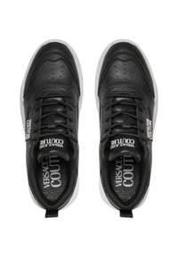 Baskets en cuir noir avec des détails perforés, des lacets plats et des accents de logo blancs sur la languette. Elles disposent d'une semelle en caoutchouc grise.