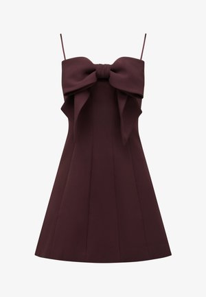 Vestito senza maniche di colore bordeaux scuro con sottili bretelle e un grande fiocco decorativo sul petto, aderente nella parte superiore e svasato nella gonna.