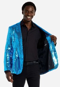 Mėlynas blizgučių švarkas su blizgiu paviršiumi, vienu mygtuku uždarymas ir juodas pamušalas. Dėvimas virš juodos marškinėlių ir kelnių.