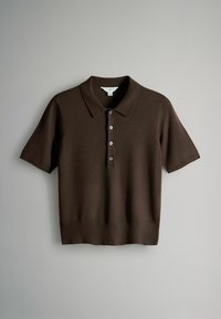 Smeđa majica s kratkim rukavima u obliku polo košulje napravljena od pletiva. Ima klasični ovratnik, pet dugmadi i rebrasti rub.