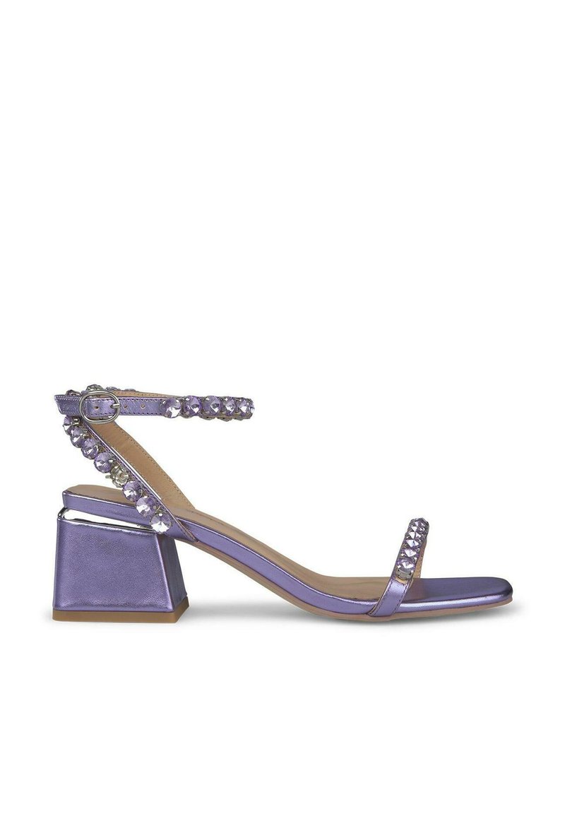 Sandalo metallico viola con tacco a blocco quadrato, adornato con strass trasparenti lungo il cinturino alla caviglia e la banda frontale. Texture liscia.