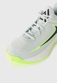 Baskets de sport gris clair avec une tige en mesh flexible, accents vert néon, surface texturée et semelle en caoutchouc. Comprend des lacets et un logo.