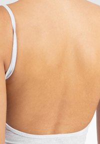 Top dos nu en maille côtelée gris clair avec des fines bretelles, doté d'une texture lisse et de côtes verticales subtiles, mettant en valeur le teint de la peau.
