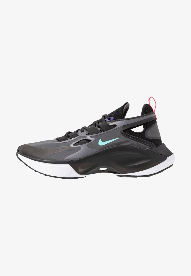 Baskets Nike noires et grises avec un swoosh bleu sarcelle, des œillets violets, une semelle blanche et un languette rouge, vues de côté sur fond blanc.