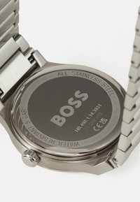 Stainless steel watch with a round case, smooth black dial, silver brand logo, side crown, and link bracelet, water-resistant to 5 bar.