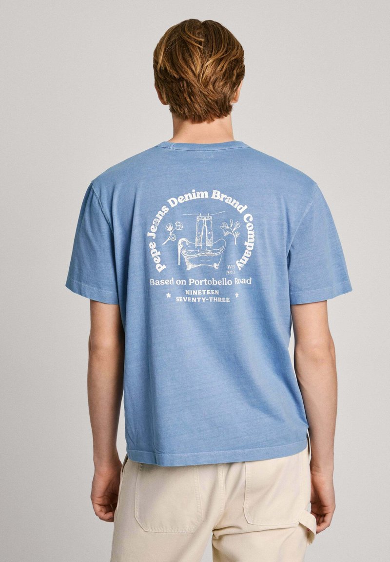 Hellblaues Baumwoll-T-Shirt mit kurzen Ärmeln, das ein weißes Druckdesign auf dem Rücken zeigt, einschließlich Text und grafischen Elementen.