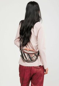 Belt bag con un mix di motivi a righe in rosa, nero e beige. Realizzata in materiale testurizzato con dettagli neri e tracolla regolabile.