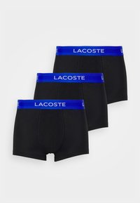 Lot de trois boxers en coton noir, avec des ceintures élastiques bleues arborrant le logo "Lacoste" et un design ajusté.