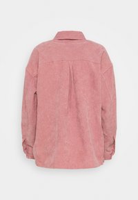 Camicia di velluto a coste color rosa con colletto, spalle scese e maniche lunghe. Include dettagli con pieghe sul retro e texture a coste.