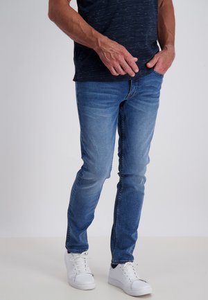 Light blue denim jeans with a slim fit, featuring a slight fade and contrasting stitching. Paired with white sneakers for a casual look.