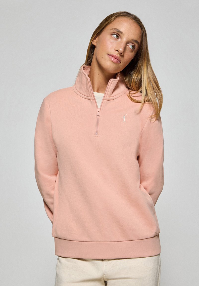 Ljusrosa zip-up sweatshirt med hög krage, ribbat nederkant och subtil logotypdetalj. Tillverkad i mjukt tyg med en slät textur.