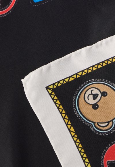 Juoda medžiaga su spalvingais grafikos atspaudais, įskaitant apvalią meškos veido iliustraciją, apsuptą balto krašto su geltonais geometriniais akcentais.