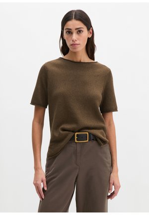 Woman wearing a brown short-sleeve knit top tucked into dark brown pants with a black belt featuring a large square gold buckle.
