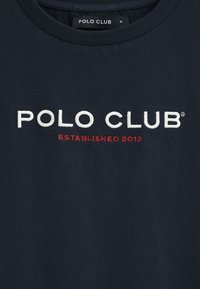 Mörkblå bomulls-T-shirt med rundad hals, prydd med vit broderad text "POLO CLUB" och röd text "ETABLERAD 2012" nedanför.