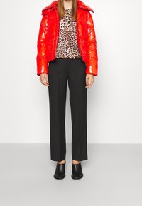 Chaqueta acolchada roja con acabado brillante, top de estampado de leopardo, pantalones negros de pierna recta y mules negros con tacón.