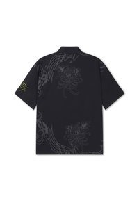 Black short-sleeve shirt with subtle dark floral and abstract patterns, featuring yellow graphic text on left sleeve and a collar.