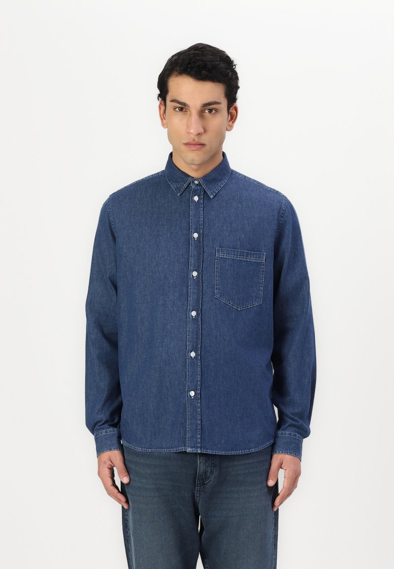 Denim overhemd in donkerblauw met een knoopsluiting kraag, voorzak, lange mouwen en een licht getailleerde pasvorm. Gladde textuur en klassiek ontwerp.