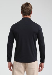 Camisa de manga larga de color azul marino oscuro con cuello, diseño ajustado y puños abotonados. El material parece suave con un ligero brillo.