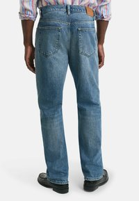 Hellblaue Denim-Jeans mit geradem Schnitt, zwei Gesäßtaschen, dezenten Verwaschungen und einem beigefarbenen Lederpatch am Bund.