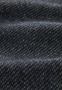 Texturerad tyg med en mörk marinblå bas, som har ett fläckigt mönster i ljusare grå nyanser och visar en mjuk, vävd look.