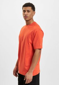 Oranges Baumwoll-T-Shirt mit kurzen Ärmeln und Rundhalsausschnitt, mit einer lässigen Passform und einem dezenten Logo-Detail am Ärmel.