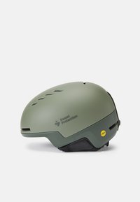 Casco verde con finitura opaca, dotato di aperture per la ventilazione e etichetta MIPS. Forma arrotondata liscia, design ergonomico con imbottitura interna.