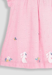 Vestido de algodón rosa con puntos texturizados, conejitos bordados y acentos florales. Mangas cortas y un diseño acampanado en el dobladillo.