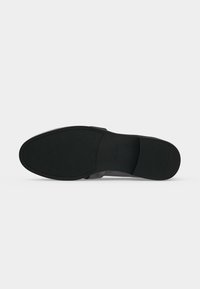 Semelle d'une chaussure habillée noire avec surface texturée pour l'adhérence et le nom de la marque ALDO embossé au niveau de la voûte plantaire.