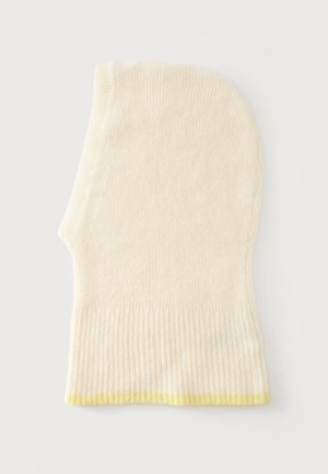 Passamontagna lavorato a maglia color crema con bordo a coste e leggero rifinitura gialla in basso, posato disteso su una superficie bianca.
