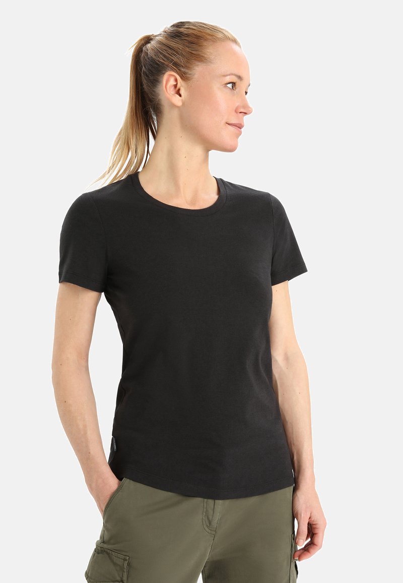 T-shirt nera in cotone con maniche corte e scollatura rotonda, abbinata a pantaloni cargo verdi, caratterizzati da una vestibilità slim e una texture liscia.