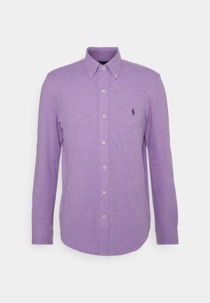Camicia a maniche lunghe color lavanda con colletto button-down, realizzata in tessuto strutturato, con un piccolo logo scuro sul petto sinistro e bottoni bianchi.