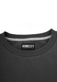 Mörkgrå sweatshirt med en ribbad halsringning och en etikett med texten "HONESTY RULES" i vit skrift. Mjuk tygtextur.