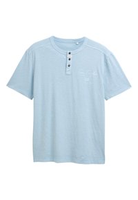 Camiseta de manga corta azul claro con cuello redondo, tapeta de botones en la parte delantera y un diseño impreso sutil en el pecho. Textura suave.