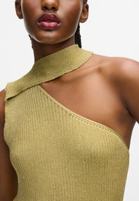 Asymetrický top na jedno rameno z metalickej zlatej úpletu, s rebrovanou textúrou a širokým golierom, ktorý obopína krk.